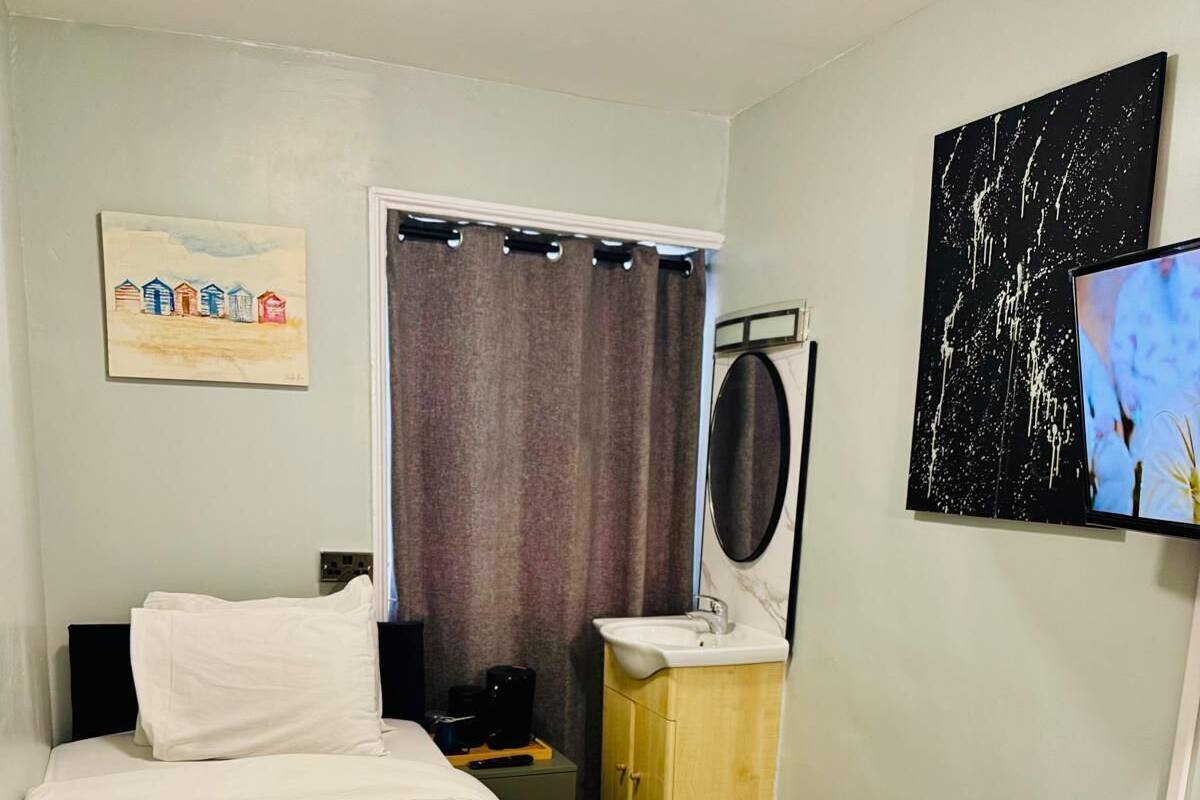 A hotel room with a bed, a wooden dresser, a television, and a painting on the wall.