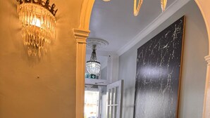 A hallway with a chandelier, a fire extinguisher, and a door leading to an outdoor area. - Sachi Hotel (Brighton)