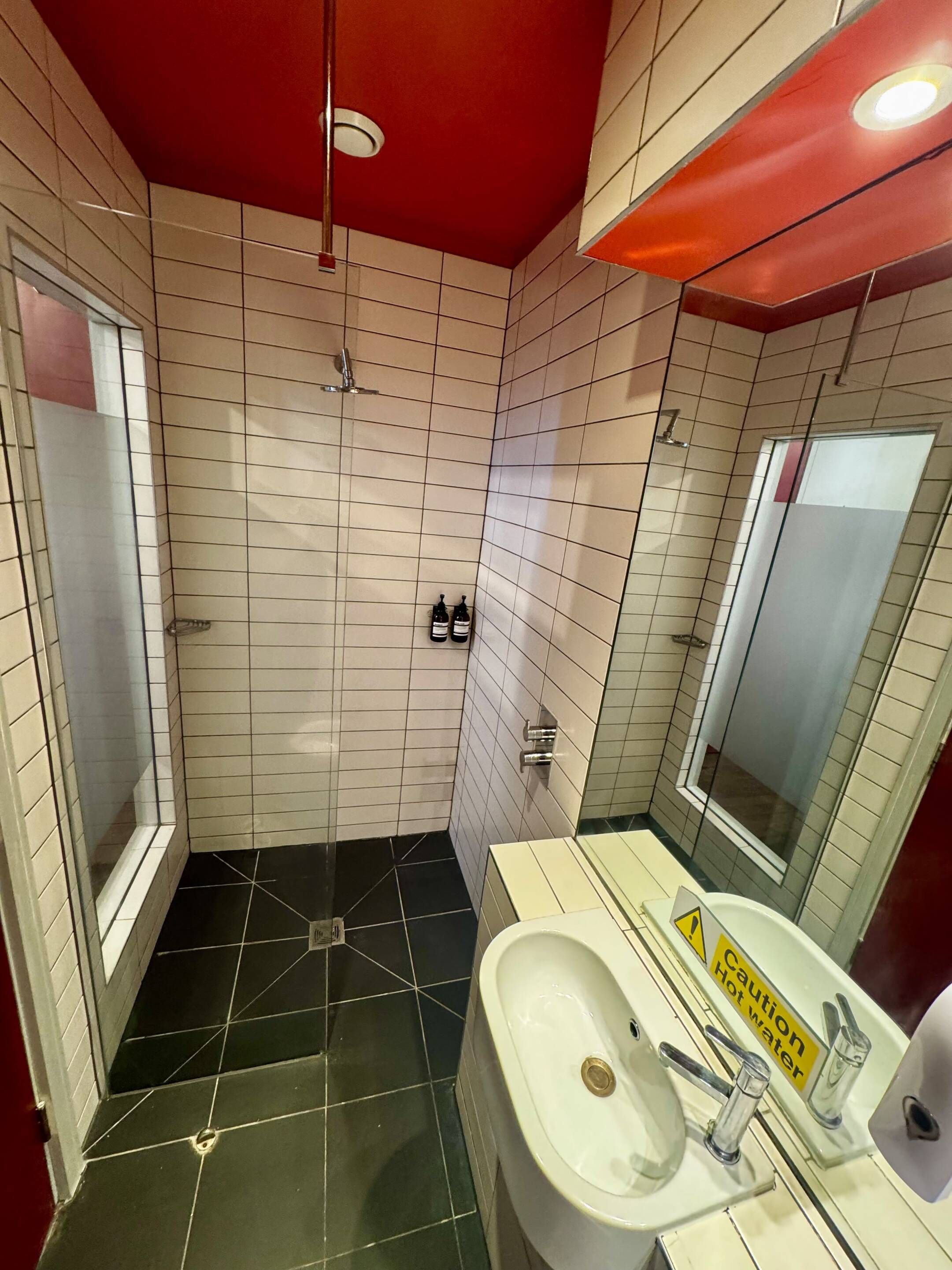 Un baño con ducha, lavamanos y espejo.