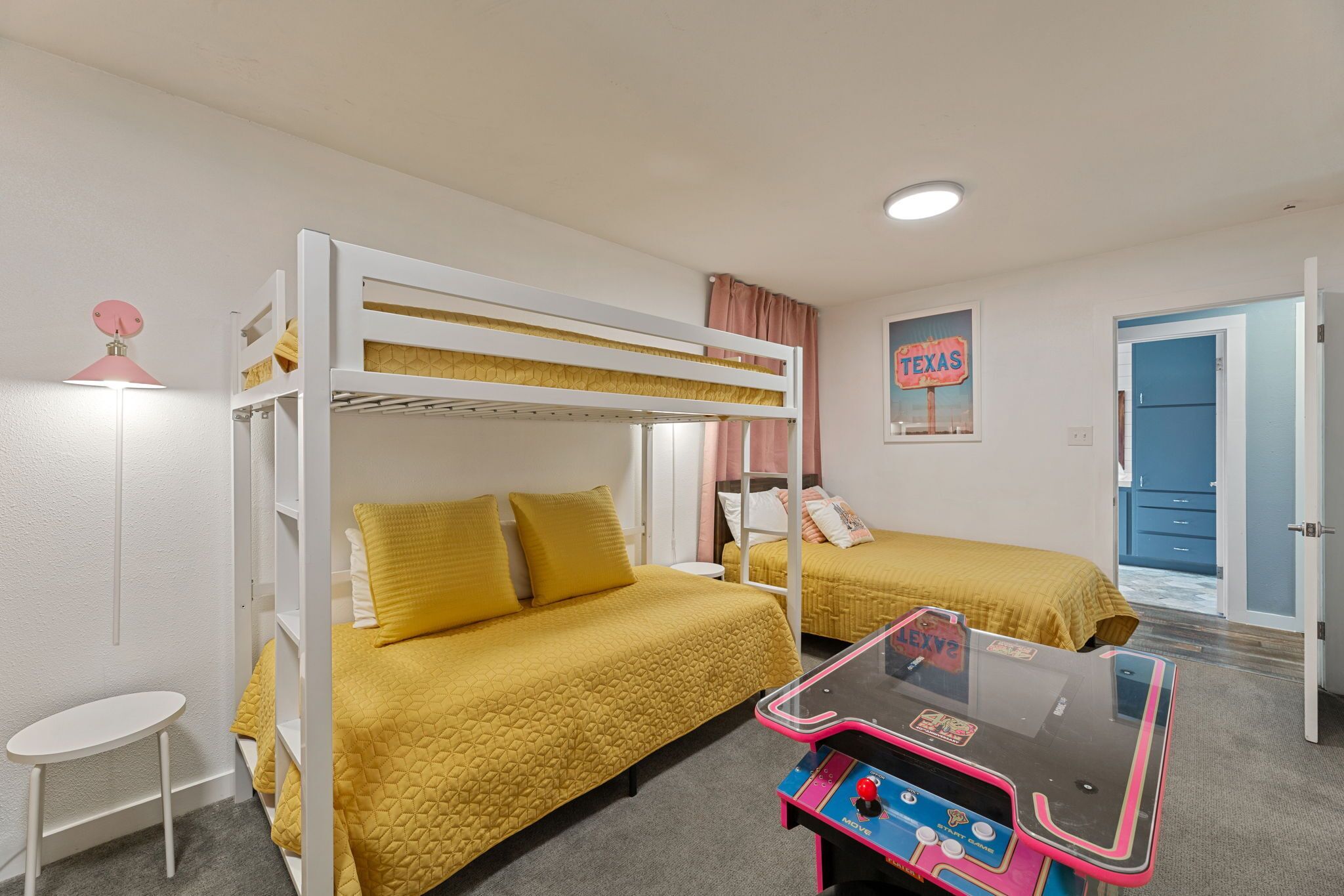 A room with bunk beds, a small table, and a gaming console.
