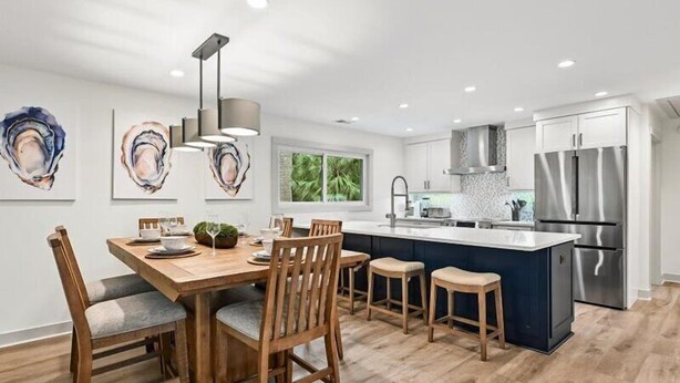Een moderne keuken met een centraal eiland, een houten eettafel en stoelen.