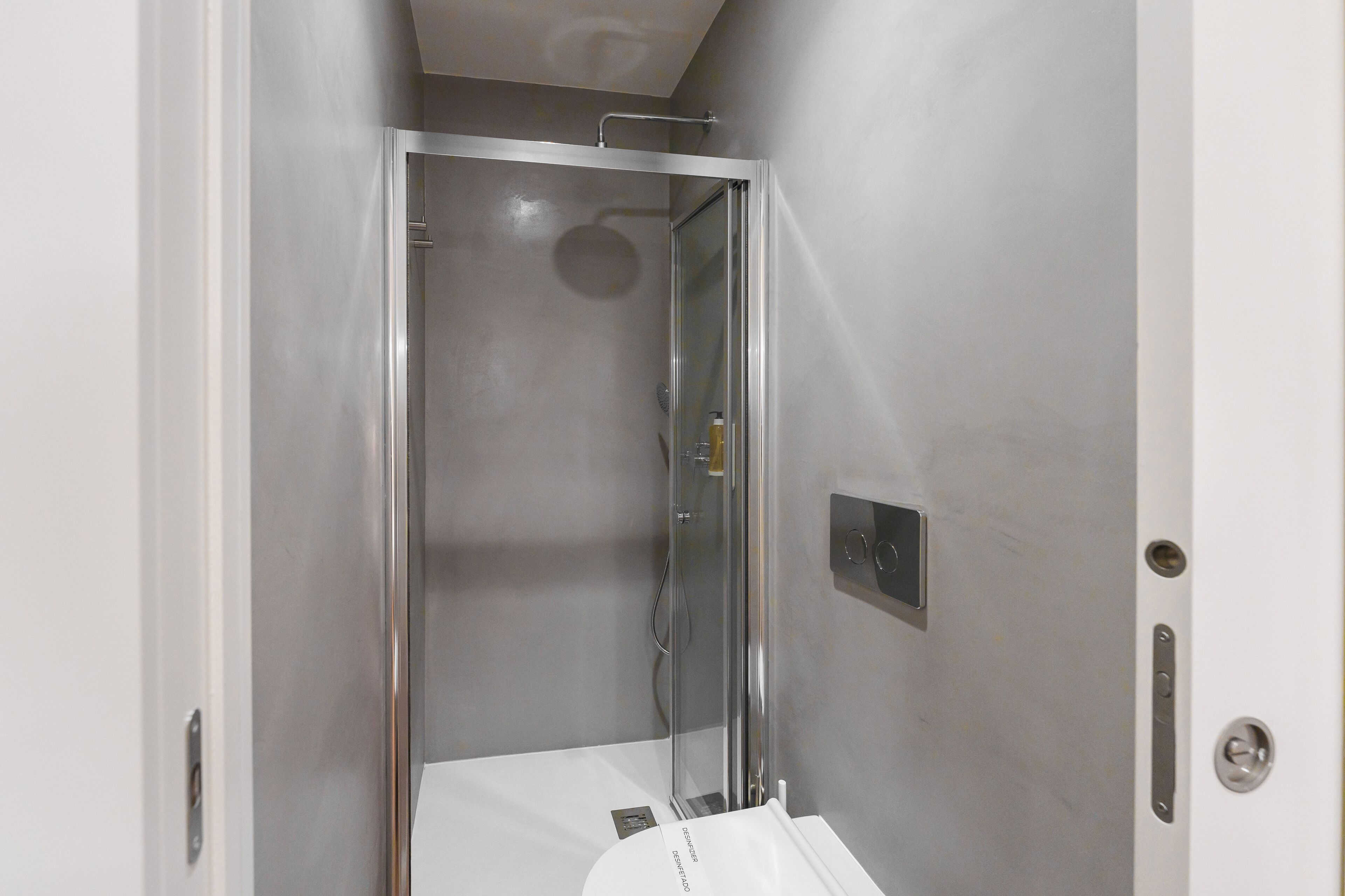 A bathroom with a glass-enclosed shower, a white sink, and a wall-mounted light fixture.
