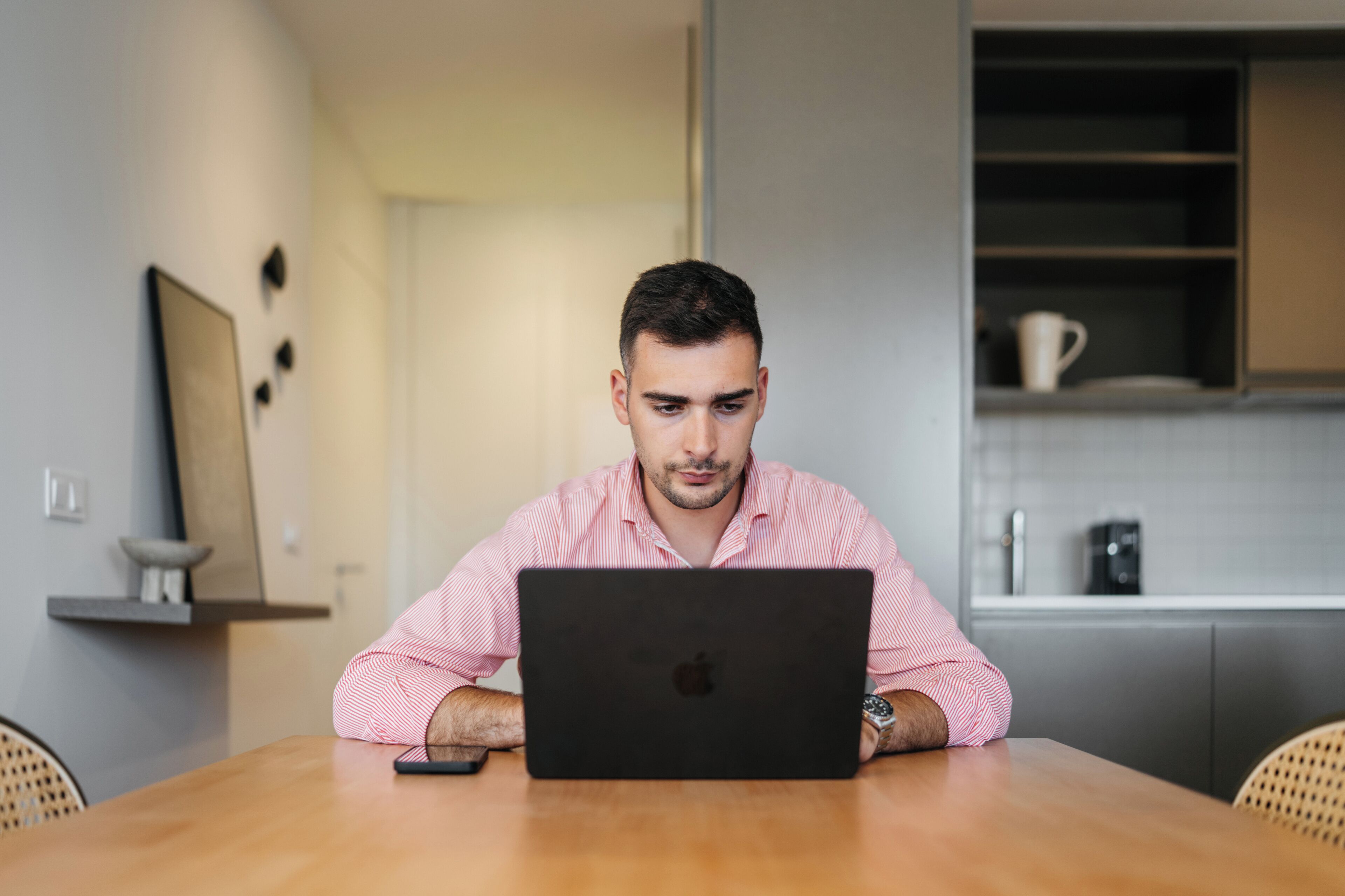 A person sitting at a wooden table with a laptop.