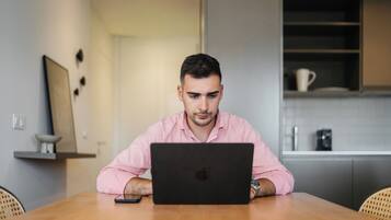 A person sitting at a wooden table with a laptop.