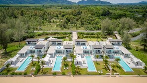 Un moderno resort con varias construcciones, cada una con piscina y vistas del paisaje circundante.