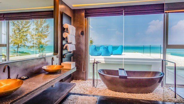 Un baño moderno con una bañera grande, un lavabo doble y vistas a la playa.