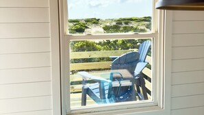Una habitación con ventana que da a una terraza con sillas y una mesa.