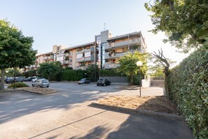 A multi-story residential building with balconies, a parking lot, and surrounding greenery. - GuestHost - La Casa di Polly (Bitritto)