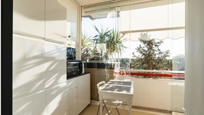 A modern kitchen with white cabinets, a black microwave, and a dining area with a table and chairs. - GuestHost - La Casa di Polly (Bitritto)