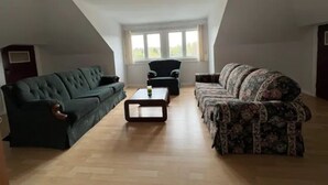 Un loft spacieux avec un plafond haut, deux canapés, une table basse et une grande fenêtre laissant entrer la lumière naturelle.