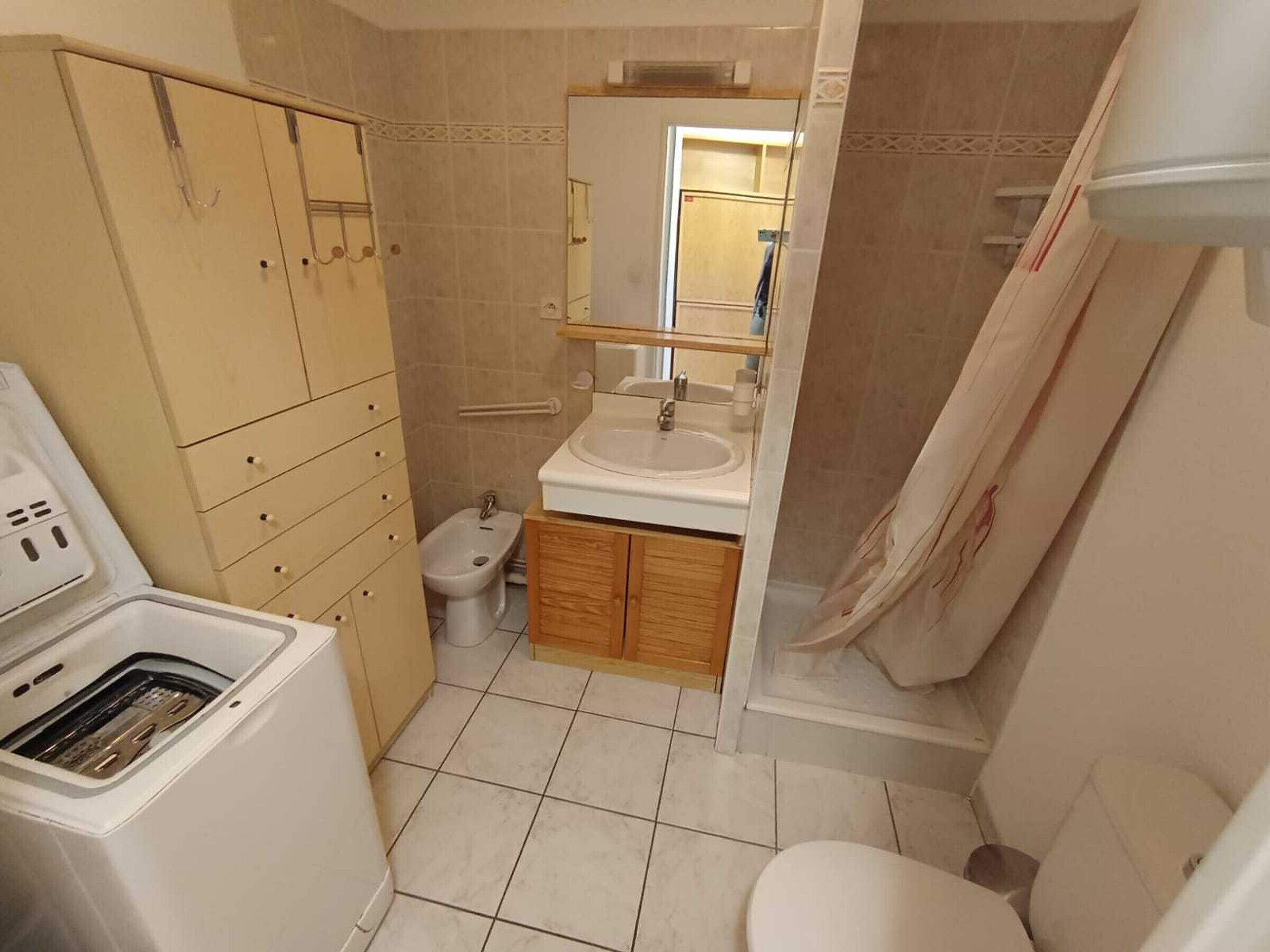 A compact bathroom with a toilet, bidet, sink, and a shower area.