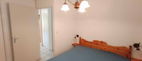 A bedroom with a wooden bed, a white door, and a chandelier.