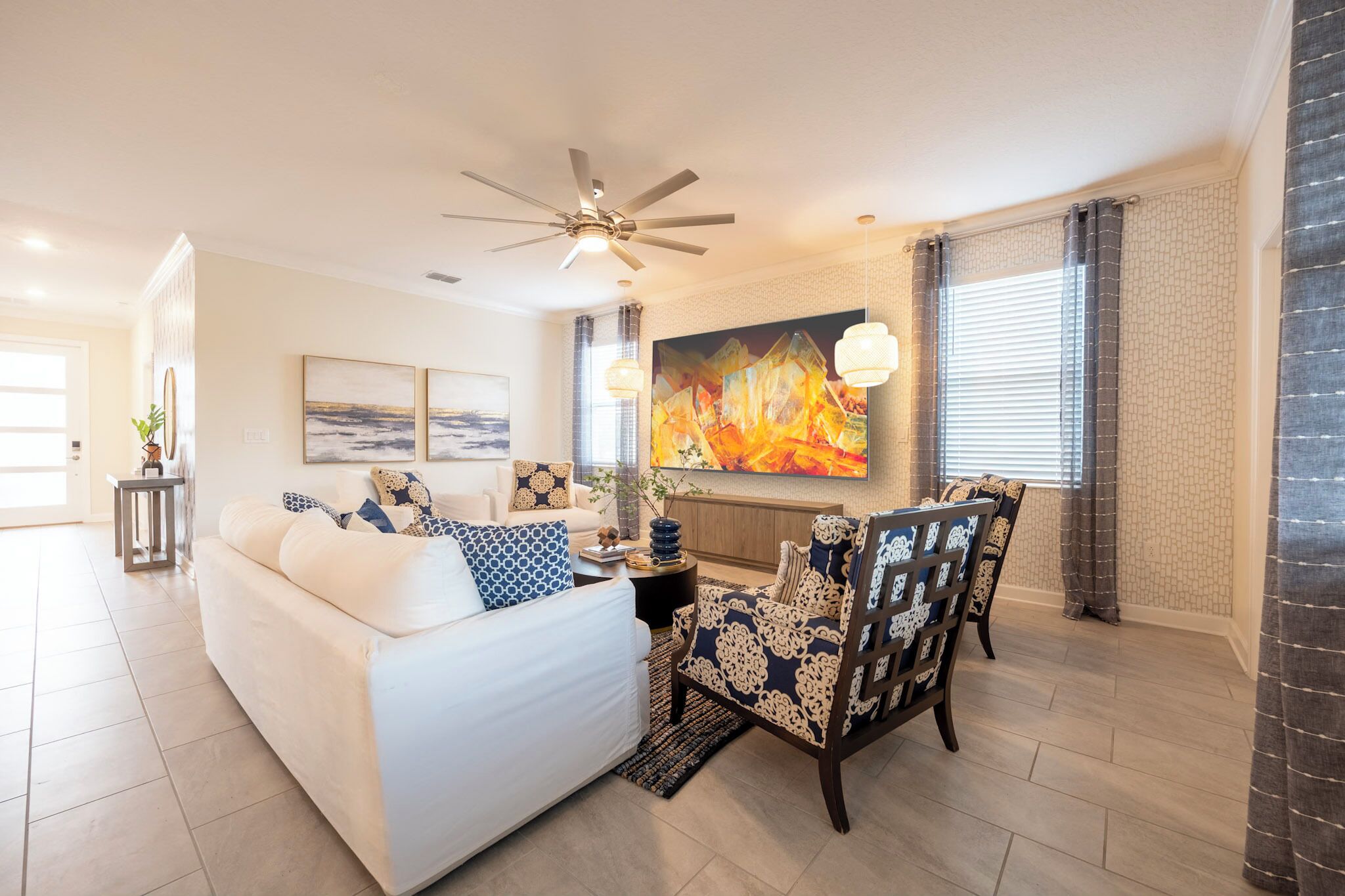 A modern living room with a white sofa, patterned armchair, and a ceiling fan.