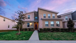 A modern two-story residential building with a stone facade, a red front door, and a well-maintained lawn. - Amazing 6BR Villa Private Pool & Theater (Kissimmee)