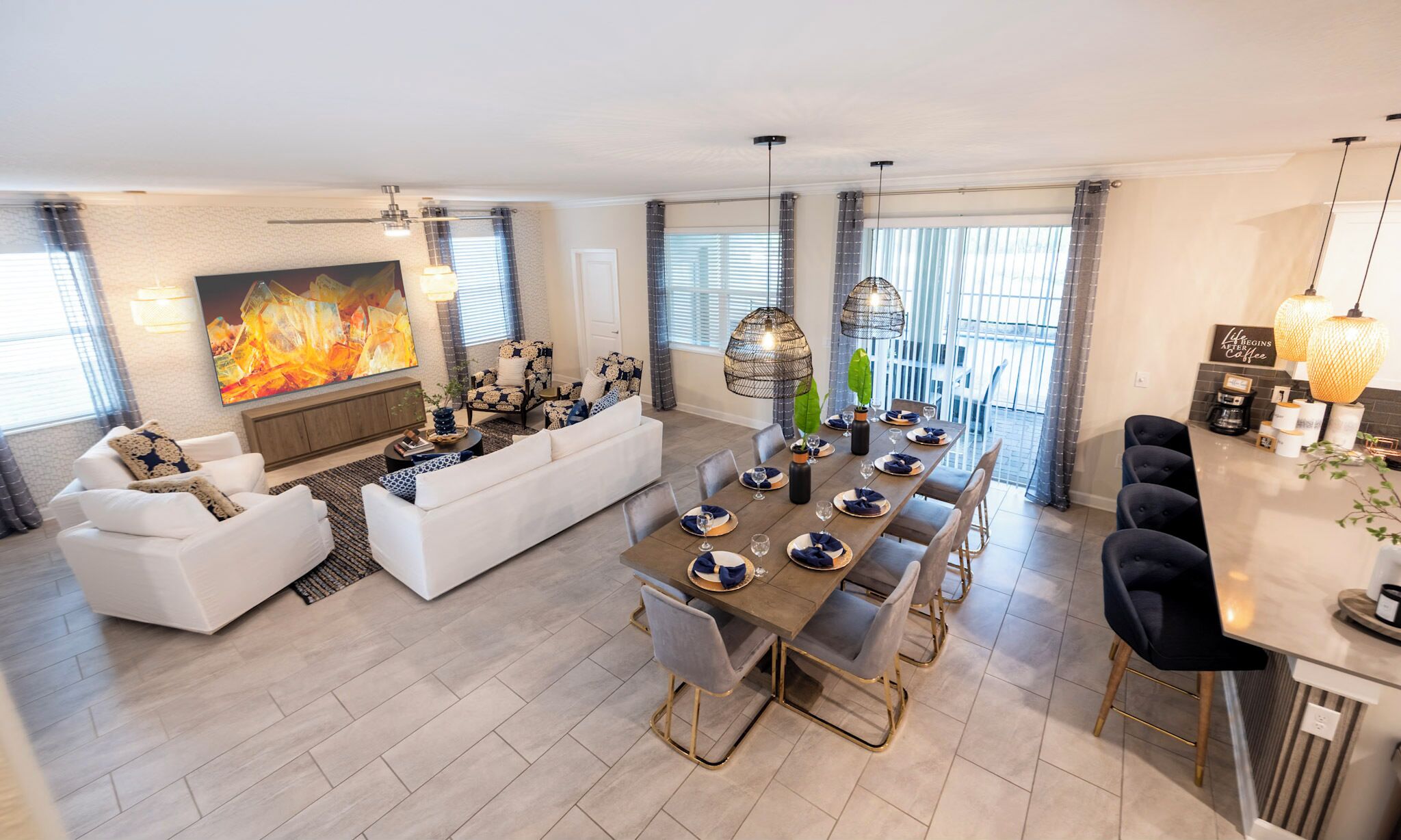 Een moderne woonkamer met een grote televisie, een open haard en een eethoek met een lange tafel voor zes personen.