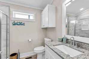 Une salle de bain avec des toilettes blanches, un lavabo doté d’un plan de travail en marbre et un grand miroir.