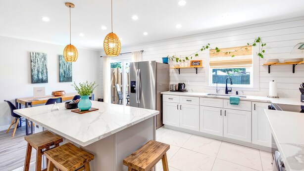 A modern kitchen with white cabinetry, a large island, and pendant lighting. - BlueJay's Nest Unit B: Game Room, Walk to Water & Stadium (Clearwater)