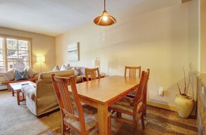 A cozy living room with a wooden dining table, comfortable seating, and a lamp. - Beautiful Condo in Passage Point! PP606 (Copper Mountain)