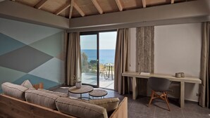 Ein modernes Zimmer mit Holzboden, einer Couch, einem Schreibtisch und Meerblick.