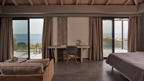 Ein Schlafzimmer mit einem großen Bett, einem Schreibtisch und Blick aufs Meer.