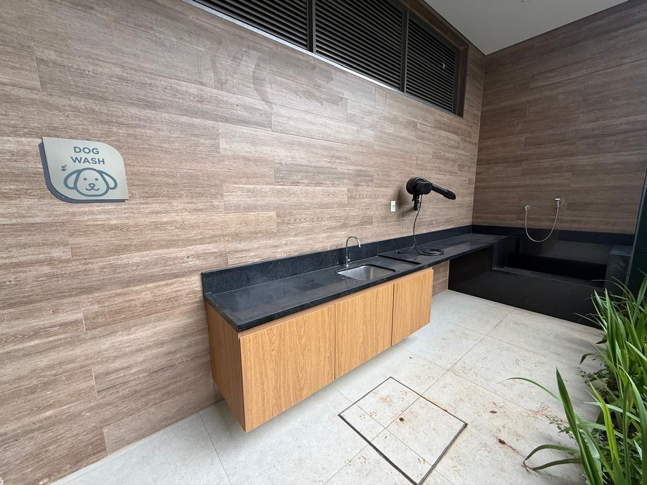 A modern kitchen with a wood-textured backsplash, a black countertop, and a dog wash sign.