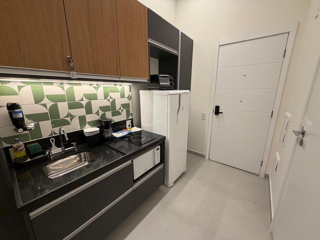 A modern kitchen with a black countertop, a sink, a microwave, and a refrigerator.