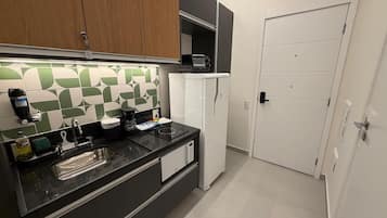 A modern kitchen with a black countertop, a sink, a microwave, and a refrigerator.