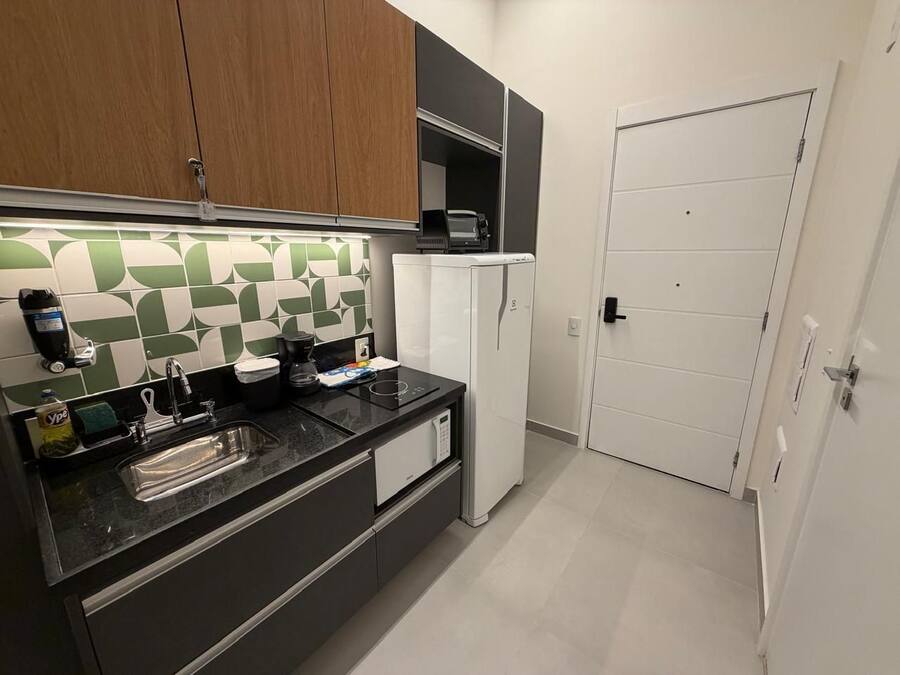 A modern kitchen with a black countertop, a sink, a microwave, and a refrigerator.
