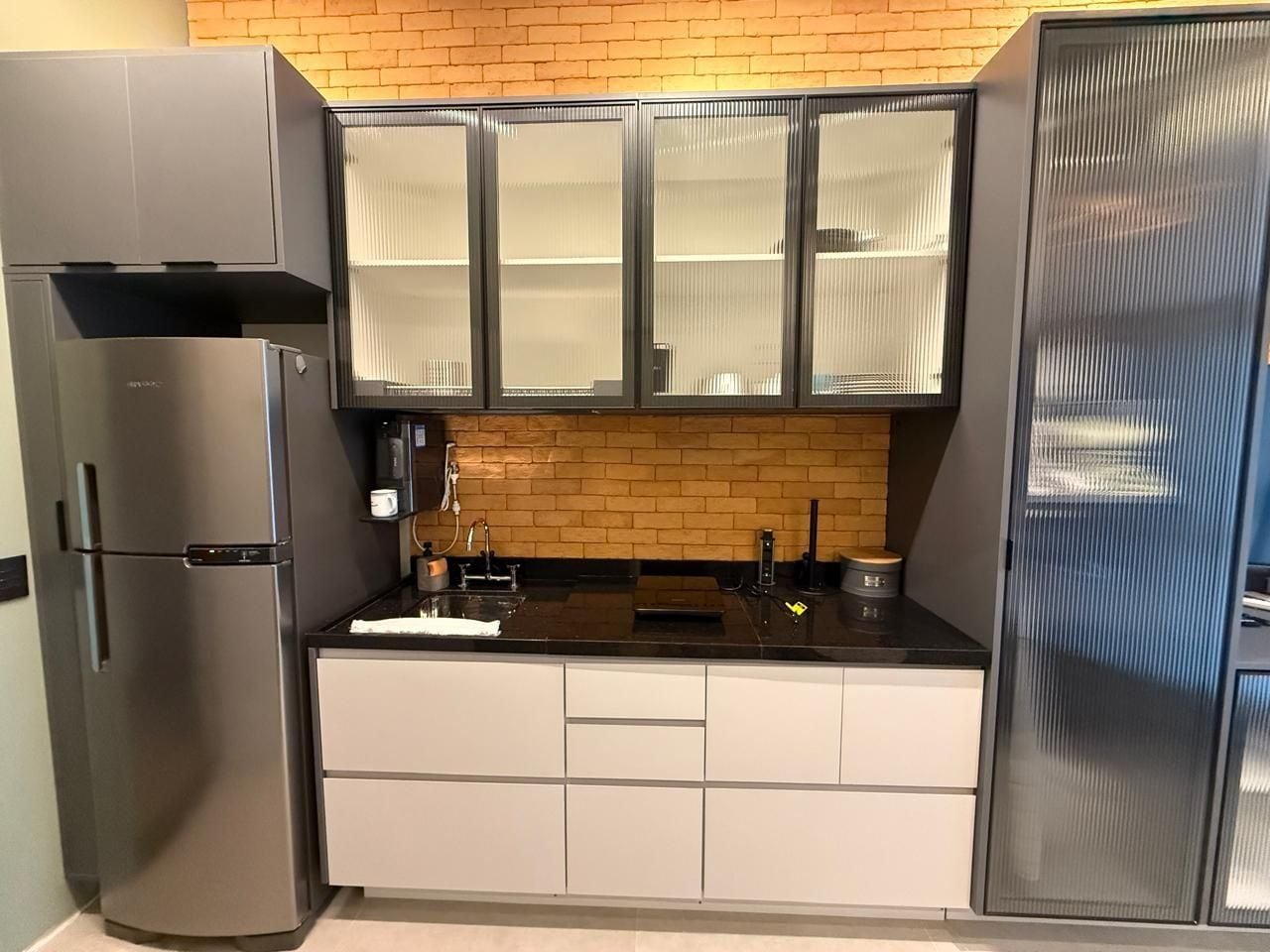 A compact kitchen with a refrigerator, a sink, and cabinets.