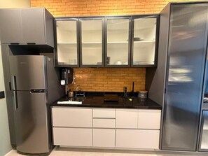 Cocina compacta con refrigerador, pileta y alacenas.