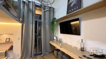 A modern kitchen with a built-in stove, a flat-screen TV mounted above the counter, and a sliding glass door leading to a balcony.