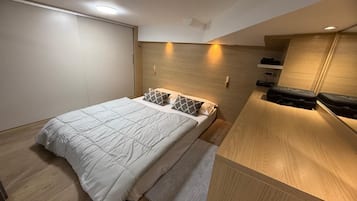 A modern bedroom with a bed, wooden headboard, and built-in storage.