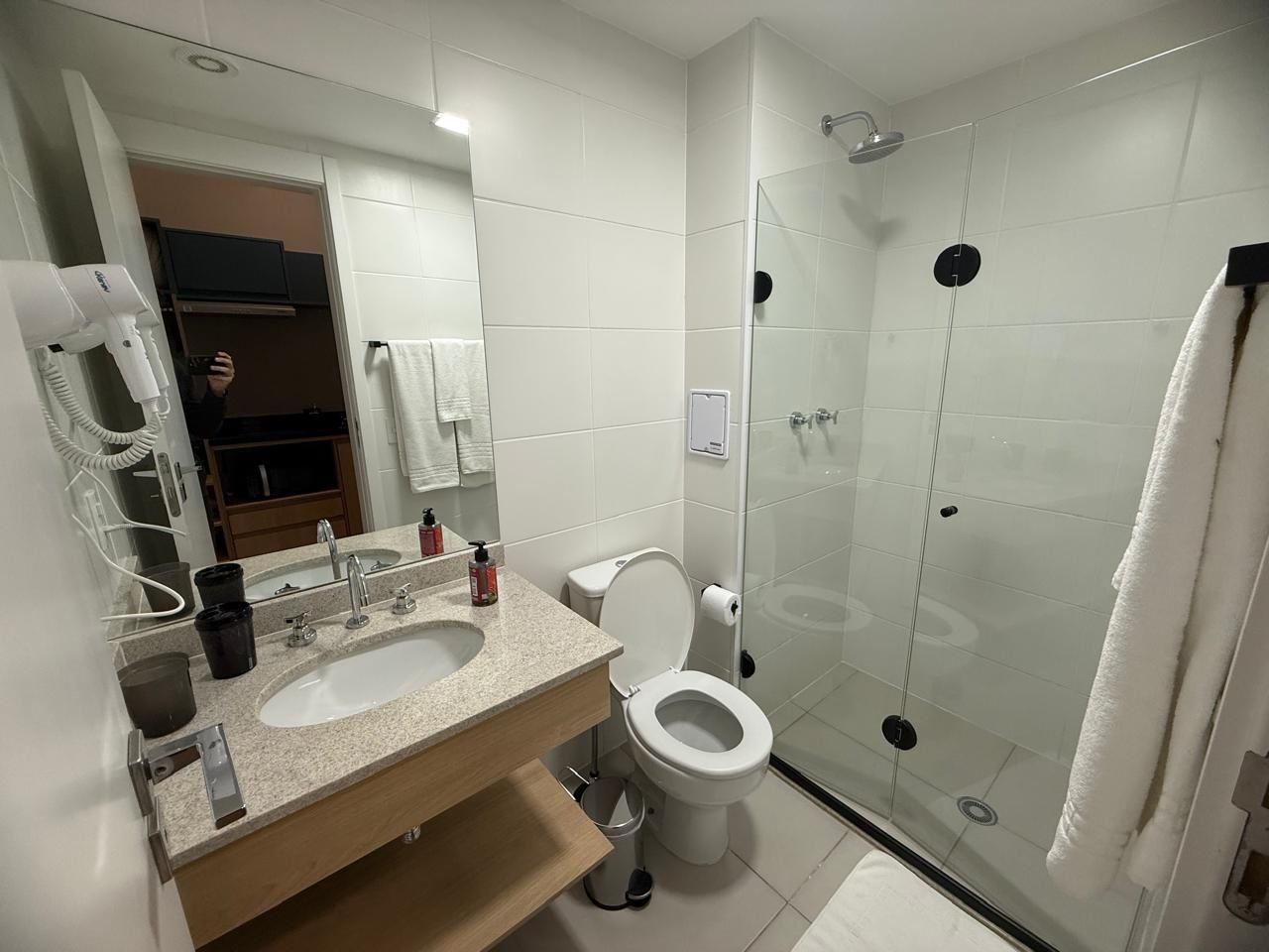 Un baño moderno con lavabo, inodoro y ducha con mampara de vidrio.