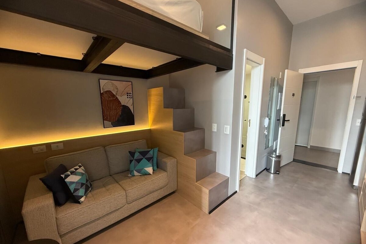Un intérieur moderne avec un canapé, un escalier et un couloir menant à une porte.