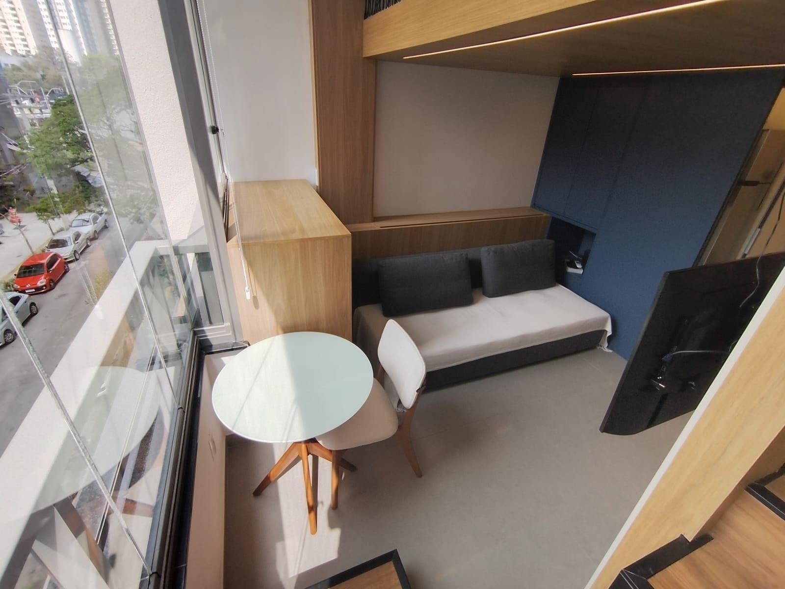 Un intérieur moderne avec un canapé, une petite table ronde et une vue sur la rue.