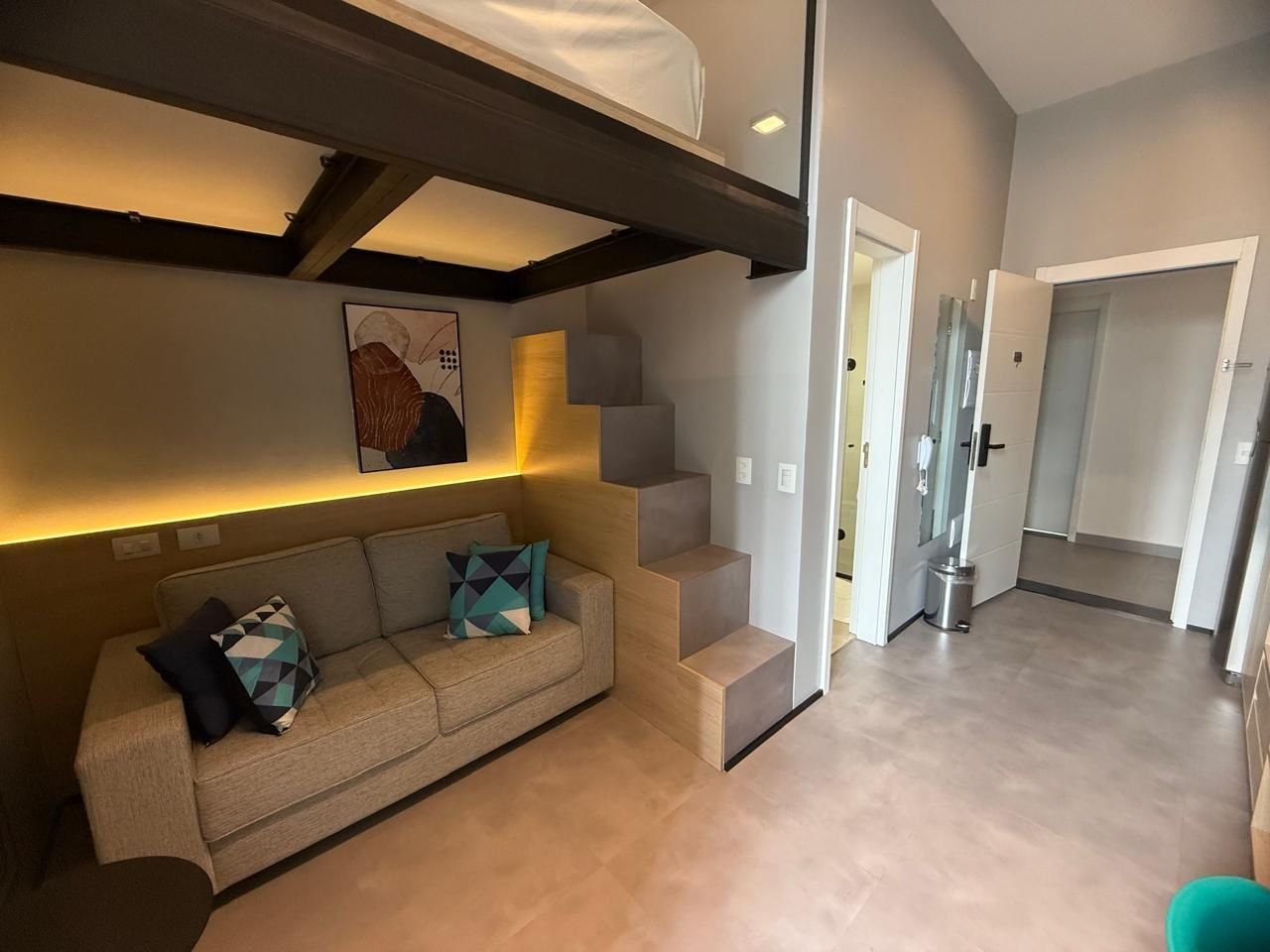 Een modern interieur met een bank, een trap en een gang die naar een deur leidt.