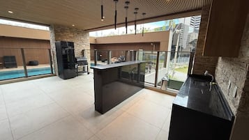 A spacious kitchen with a large island, a built-in oven, and a view of a swimming pool.