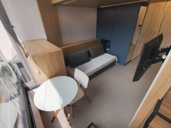 Una habitación pequeña con sofá, una mesita y televisor.