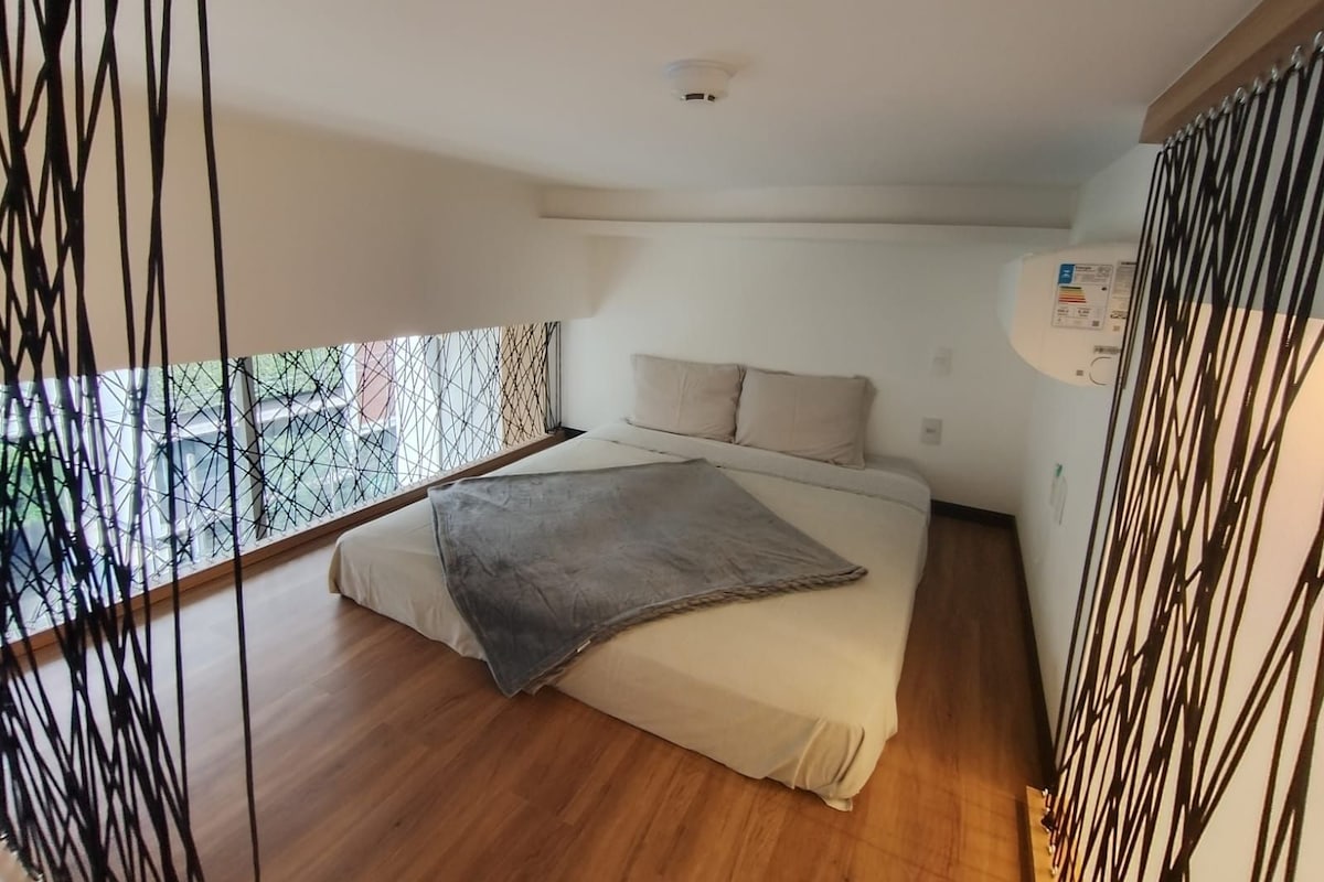 Un dormitorio con cama, ventana y aire acondicionado instalado en la pared.