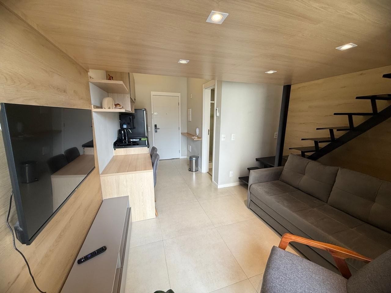 Uma sala de estar moderna com televisão de tela plana, sofá, mesa de centro e escada.