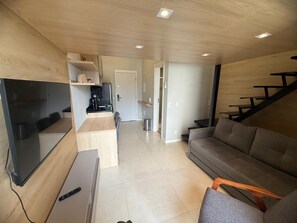 Ein modernes Wohnzimmer mit Flachbildfernseher, einer Couch, einem Couchtisch und einer Treppe.