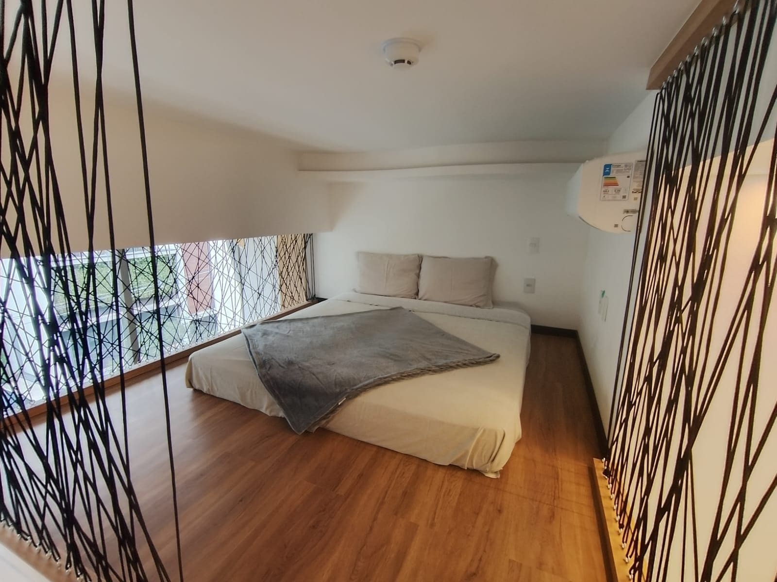 A bedroom with a bed, a window, and a ceiling light.