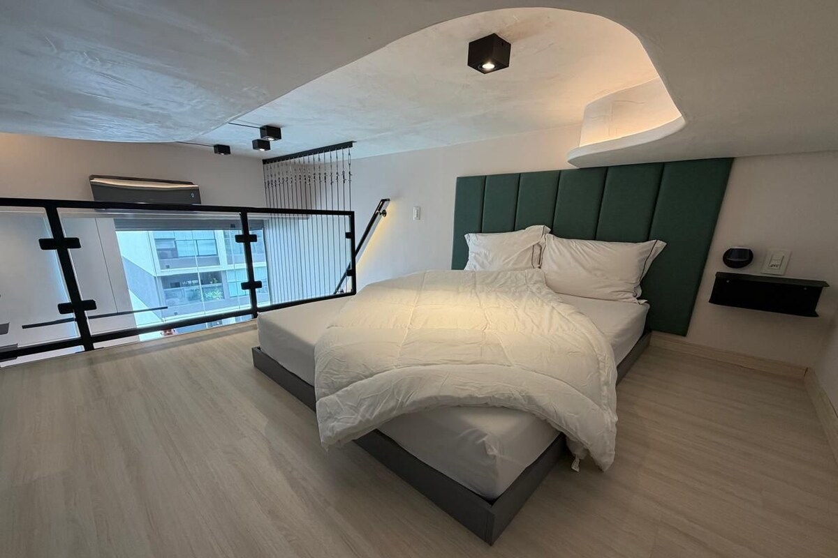 Een moderne slaapkamer met een bed, een nachtkastje, een wandplank en een balkon met een hekwerk.