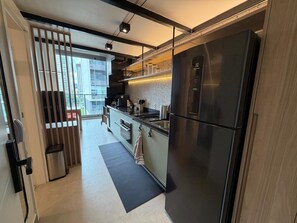 Una cocina moderna con un refrigerador de acero inoxidable, un horno empotrado y una ventana con vista a la ciudad.