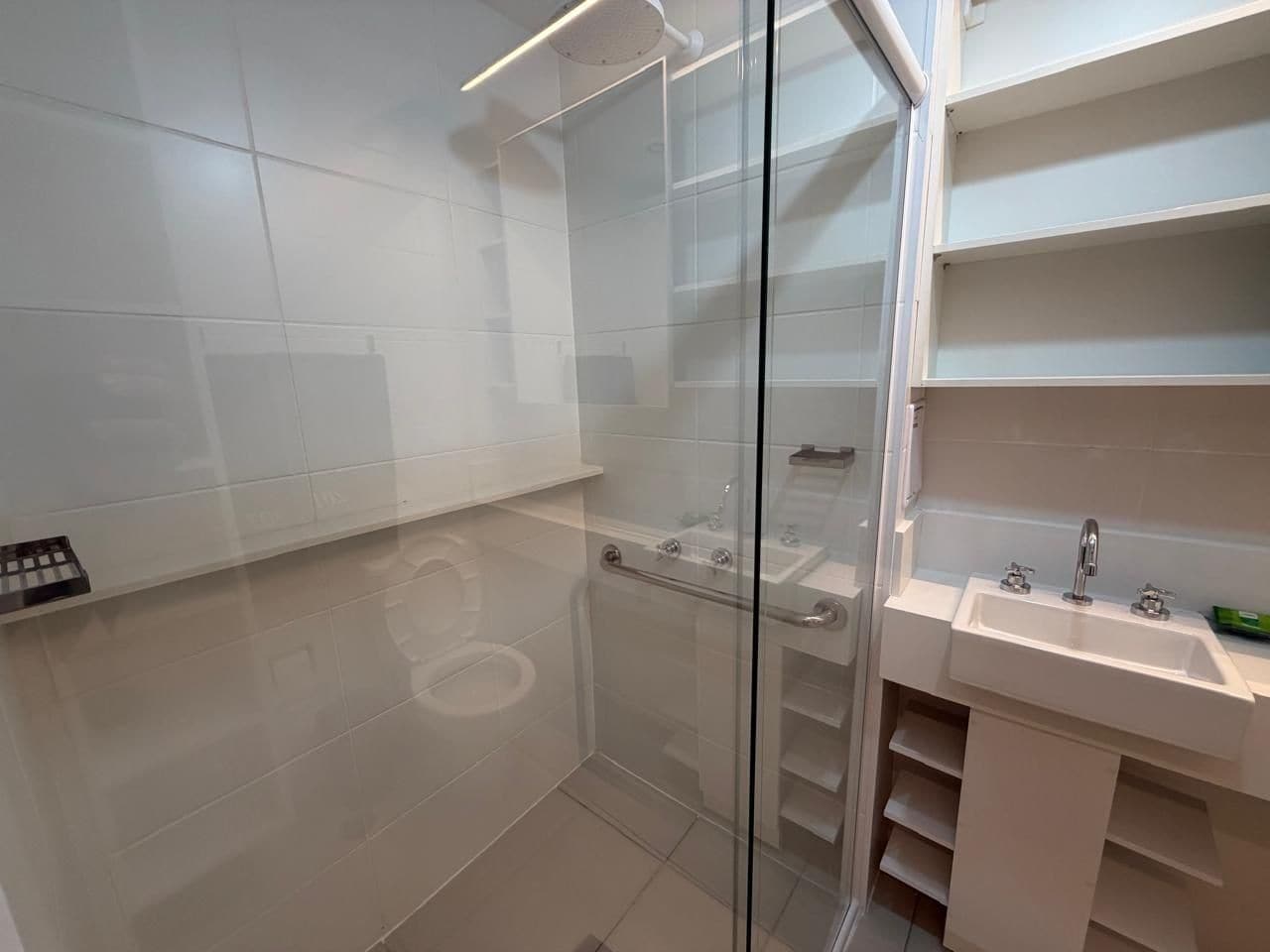 A modern bathroom with a glass shower enclosure, a white sink, and a toilet.