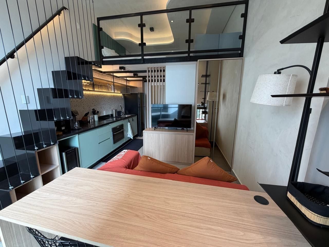 Une cuisine moderne avec un coin repas, un escalier et un petit espace détente avec des coussins.