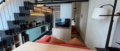 Une cuisine moderne avec un coin repas, un escalier et un petit espace détente avec des coussins.