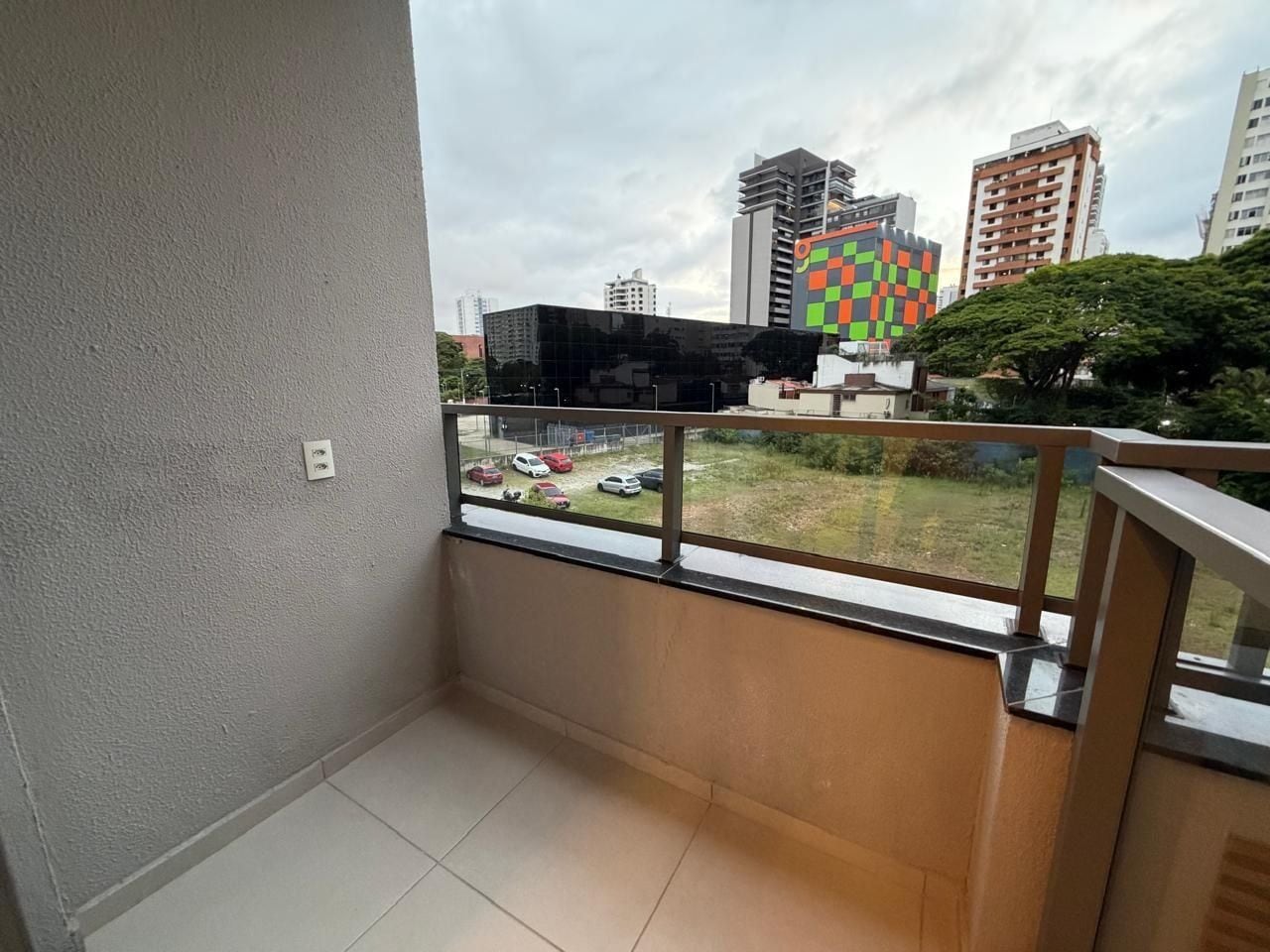 A balcony with a view of a parking lot and buildings.