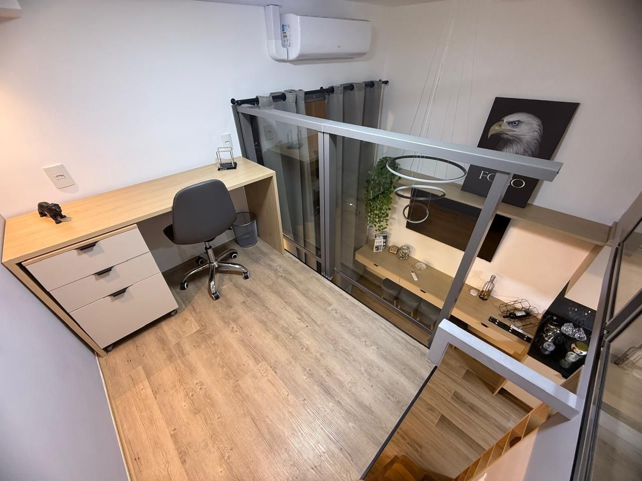 A compact office space with a desk, chair, and a glass partition.