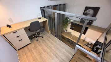 A compact office space with a desk, chair, and a glass partition.